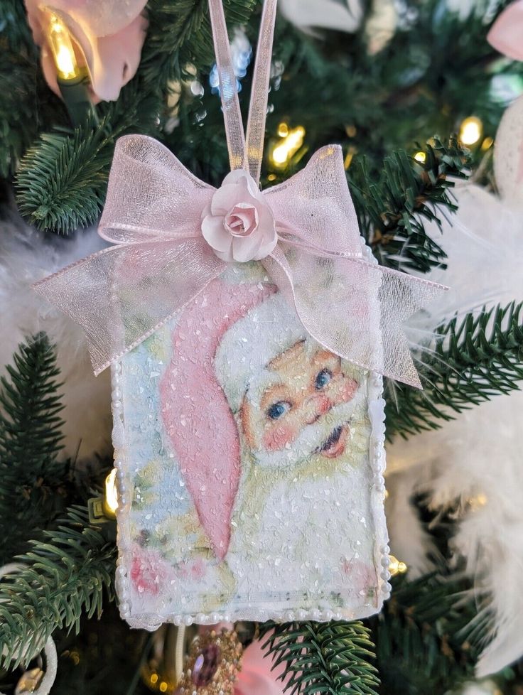 a christmas ornament hanging from a tree with pink and white ornaments on it