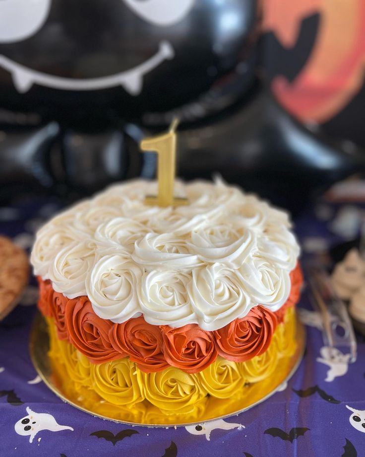 a birthday cake with white frosting and orange icing on a purple tablecloth