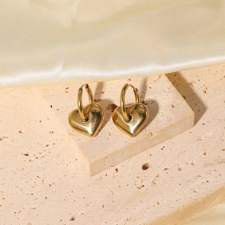 Embrace the sweet elegance of Heart Charm Earrings, beautifully crafted in 18k gold plating. These earrings feature charming heart charms, perfect for adding a touch of love and sophistication to any ensemble. Tarnish Resistant Gold Plated Dainty Heart Earrings, Elegant Heart Charm Huggie Earrings, Elegant Gold Plated Heart Pendant Earrings, Valentine's Day Tarnish Resistant Drop Earrings, Gold Plated Double Heart Charm Earrings, Elegant Heart Huggie Earrings For Everyday Wear, Elegant Double Heart Huggie Earrings With Heart Charm, Gold Single Heart Earring For Everyday Wear, Elegant Everyday Huggie Earrings For Valentine's Day