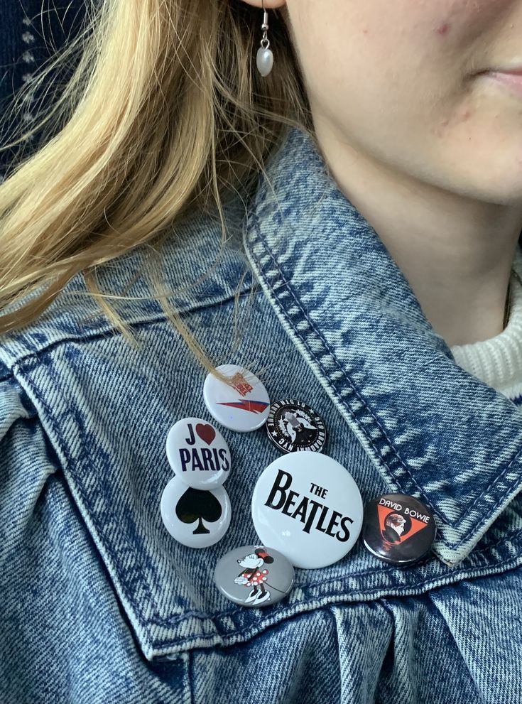 a close up of a person wearing some badges on their neck and earrings