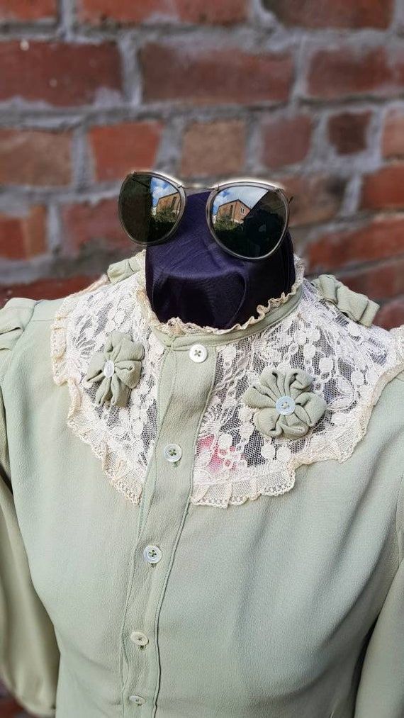 "Absolutely beautiful Vintage 1940s 50s piece here. In a line green with beautiful neckline lace embroidered detail with the button bows all the way around.  Lace looks a little off colour sue to storage plus this is 70 years old,a soak I am sure release alot of the surface dust. Arms a quite wide with padding in the shoulders and pleats at top and at the cuffs. Would look perfect tucked into a pencil skirt. A stunning piece for period film etc. Mannequin is a size 8,blouse looks a little loose top fits between a 10 and 12. Measurements as follows are.  Pit-pit 19\" Shoulder-shoulder 15\" Waist at narrowest 18&1/2 Shoulder-cuff 23&1/2\" Pit-cuff 16&1/4\" Nape-hem 24&1/2\" Pit-hem 14\" inches In cracking condition, just needs a soak to bring to life even more. Please check out my other Vint Fitted Victorian Tops With Lace Collar, Vintage Spring Tops With Lace Trim, Spring Victorian Fitted Blouse, Vintage Fashion Lace Trim Tops For Spring, Spring Victorian Long Sleeve Vintage Dress, Vintage Lace Trim Tops For Spring, Vintage Lace Trim Tops, Victorian Fitted Tops For Summer, Spring Vintage Lace Trim Tops