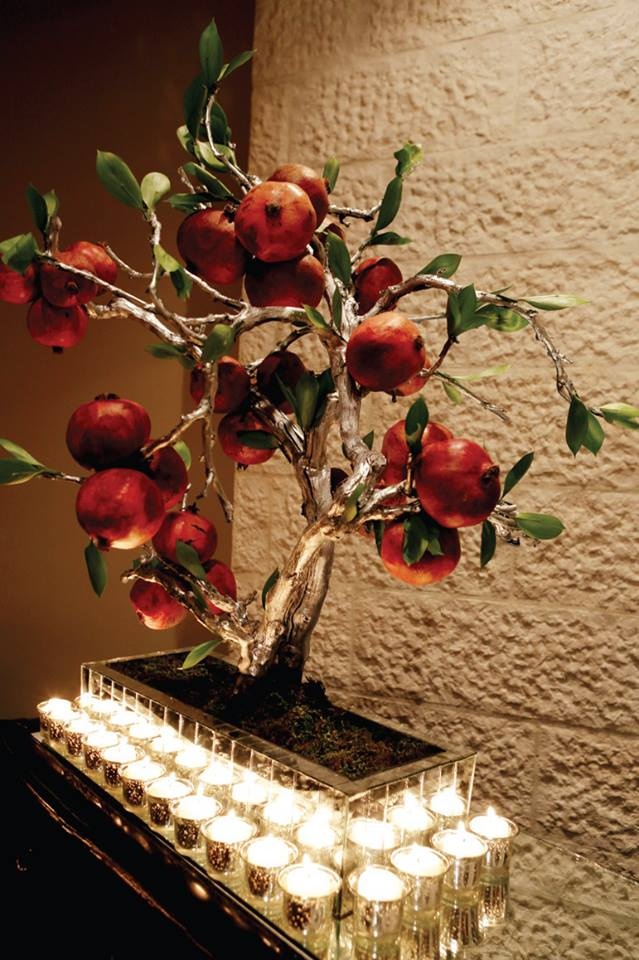 a vase filled with apples sitting on top of a table next to candles and a wall