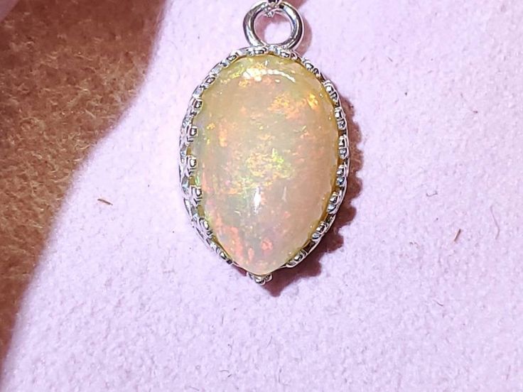 "4.00 carat green, yellow and orange natural Ethiopian opal in a Lacey bezel silver setting on a silver 18 inch chain. 5/8\" x 7/16 is the size of the stone,I will make a chain any length you like." Opal Pendant Necklace With Large Pendant, Nickel-free Oval Opal Jewelry, Opal Cabochon Round Pendant Necklaces, Opal Cabochon Round Pendant Necklace, Opal Cabochon Pendant Necklace, Gemstone Jewelry With Ethiopian Opal Round Pendant, Opal Cabochon Round Pendant Jewelry, Teardrop Opal Gemstone Necklaces, Opal Teardrop Gemstone Necklace