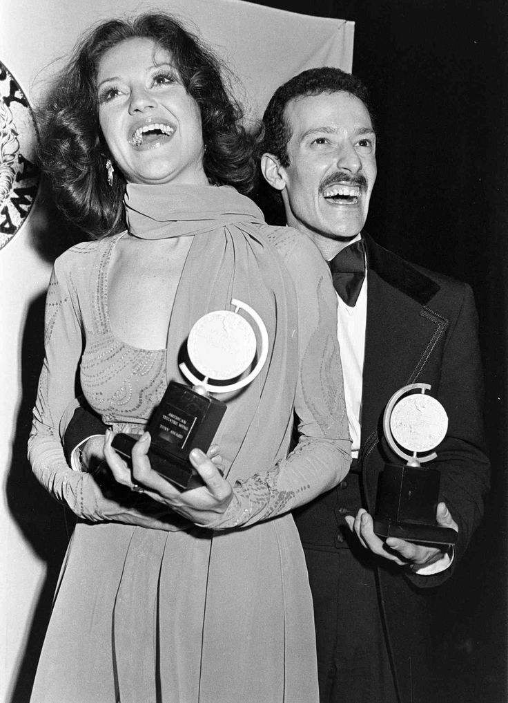 an old photo of two people holding awards