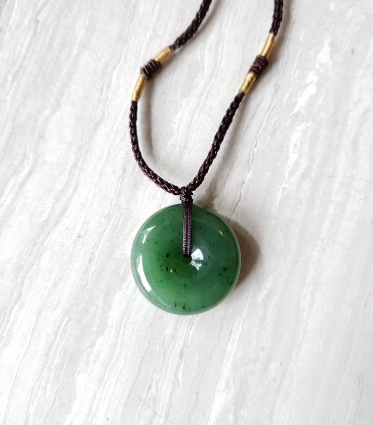 "Gorgeous green jade donut necklace. Jade pendant has a beautiful luster finish and is in a substantial size and weight. The jade is made from nephrite jade mined from British Columbia, Canada. Comes with a 24\" adjustablw hand knotted cord necklace with genuine jade beads. The pretty donut shape jade promotes good fortune and luck to the wearer. Green Jade is associated with the heart and root Chakras. Jade brings harmony and contentment to the wearer. In Asian cultures, Jade is revered as the Jade Donut Necklace, Donut Necklace, Red Stone Necklace, Spiritual Necklace, Donut Pendant, Good Luck Necklace, Aesthetic Books, Jade Crystal, Donut Shape