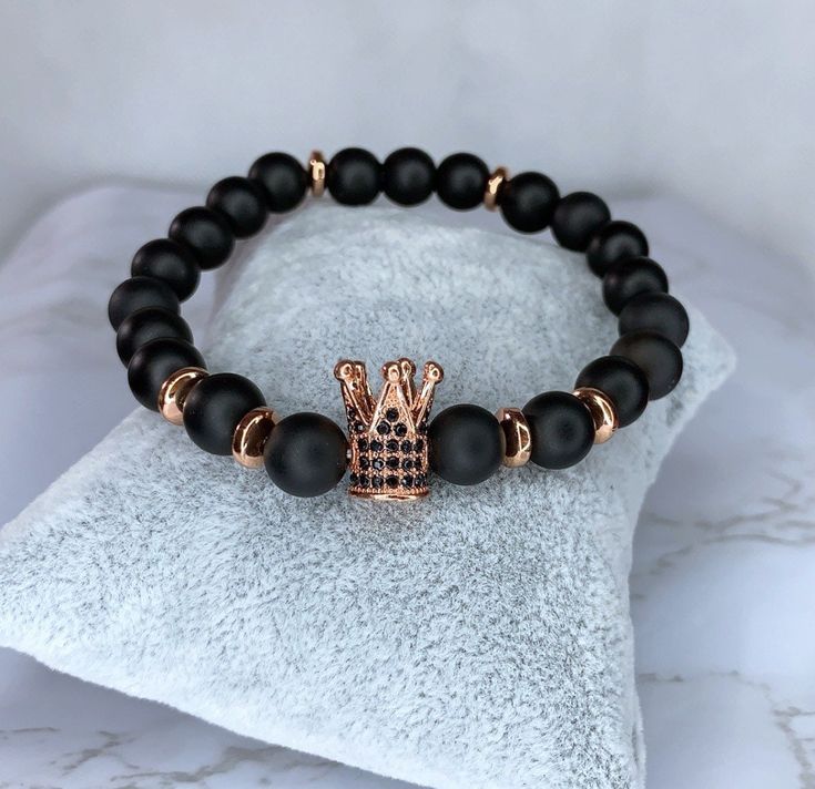 "Bracelet made with 8mm matte black onyx stones, 6mm rose gold hematite, and a rose gold and black zircon paved crown charm.  Bracelet is stretchy and made around 7\" Made by hand" Black And Rose Gold, Crown Charm, Bracelets With Meaning, Onyx Crystal, Awareness Bracelet, Rose Quartz Bracelet, Crystal Healing Bracelets, Black Onyx Stone, Onyx Bracelet