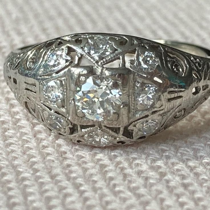 A stunning yet delicate diamond ring made at the turn of the century. This ring shows all the characteristics of the Belle Époque period. The intricately done ajour work, or cut out work is almost resemble lace. In Great Britain this style would be referred to as Edwardian. The slightly domed design sits quite low on the finger, which makes this an elegant and great piece to wear daily. This piece surely would be the most perfect engagement ring! Featuring an old European cut diamond in the cent Antique Brilliant Cut Diamond White Ring, Antique Brilliant Cut Diamond White Diamond Ring, Antique Diamond White Diamond Ring With Brilliant Cut, Victorian Diamond Ring With Diamond Accents, Antique Diamond White Diamond Ring, Victorian Style Diamond Ring With Accents, Victorian Diamond Ring With Round Cut, Victorian White Brilliant Cut Diamond Ring, White Victorian Style Brilliant Cut Diamond Ring