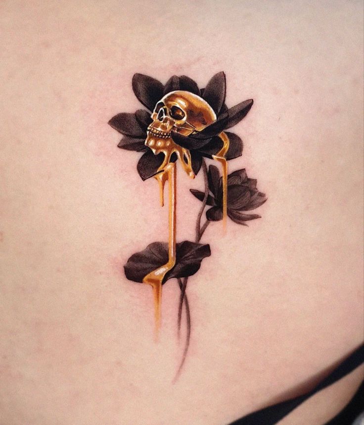 a woman's back with a skull and flower tattoo on the side of her stomach