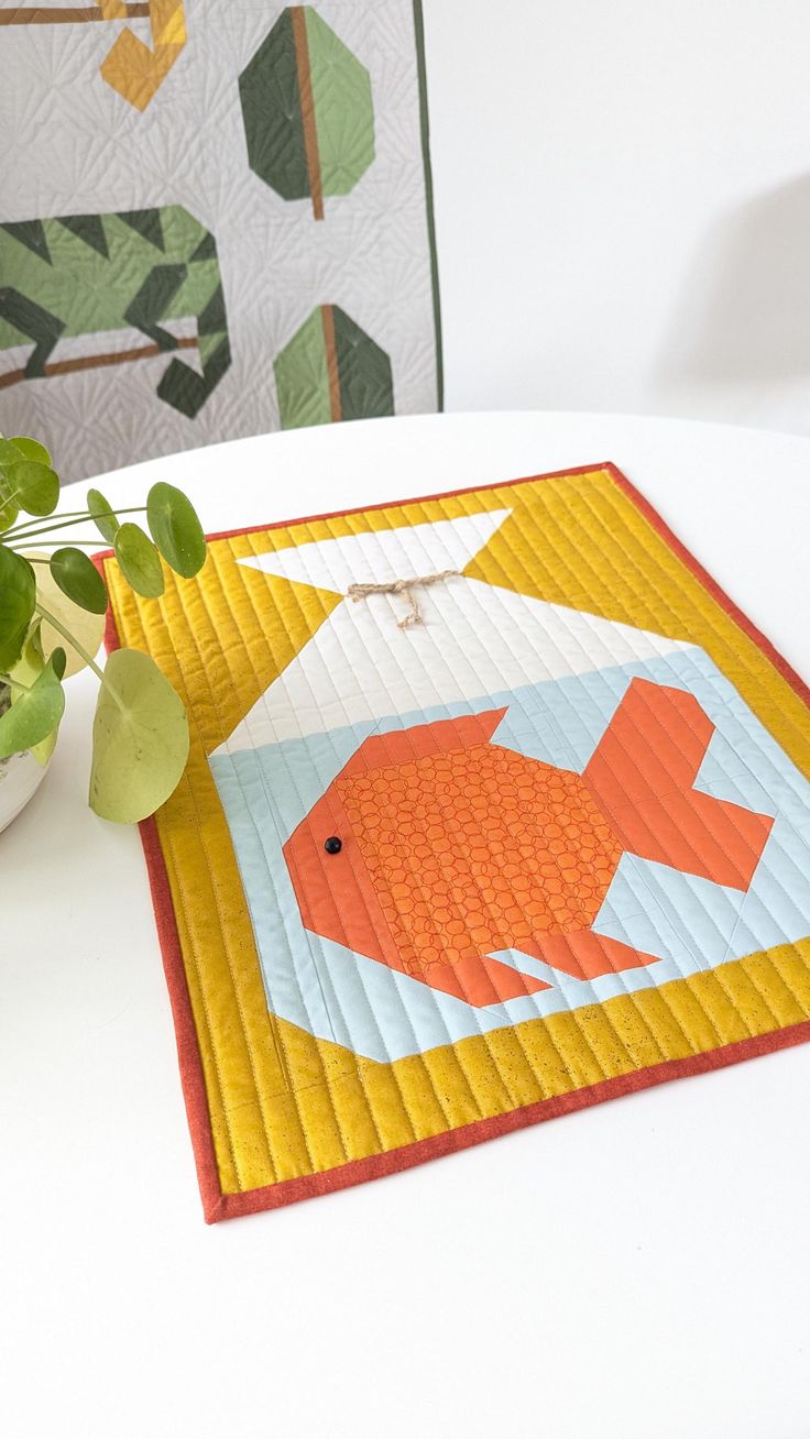 a potted plant sitting on top of a table next to a quilted fish