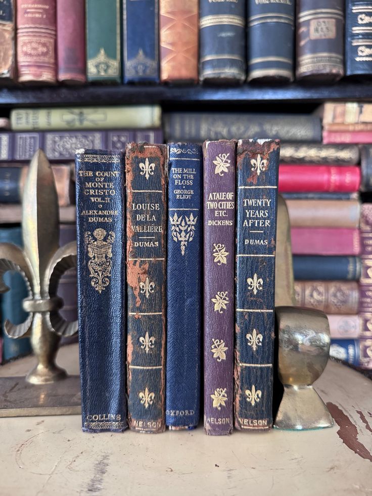 three old books sitting on top of a table next to a candle and other books