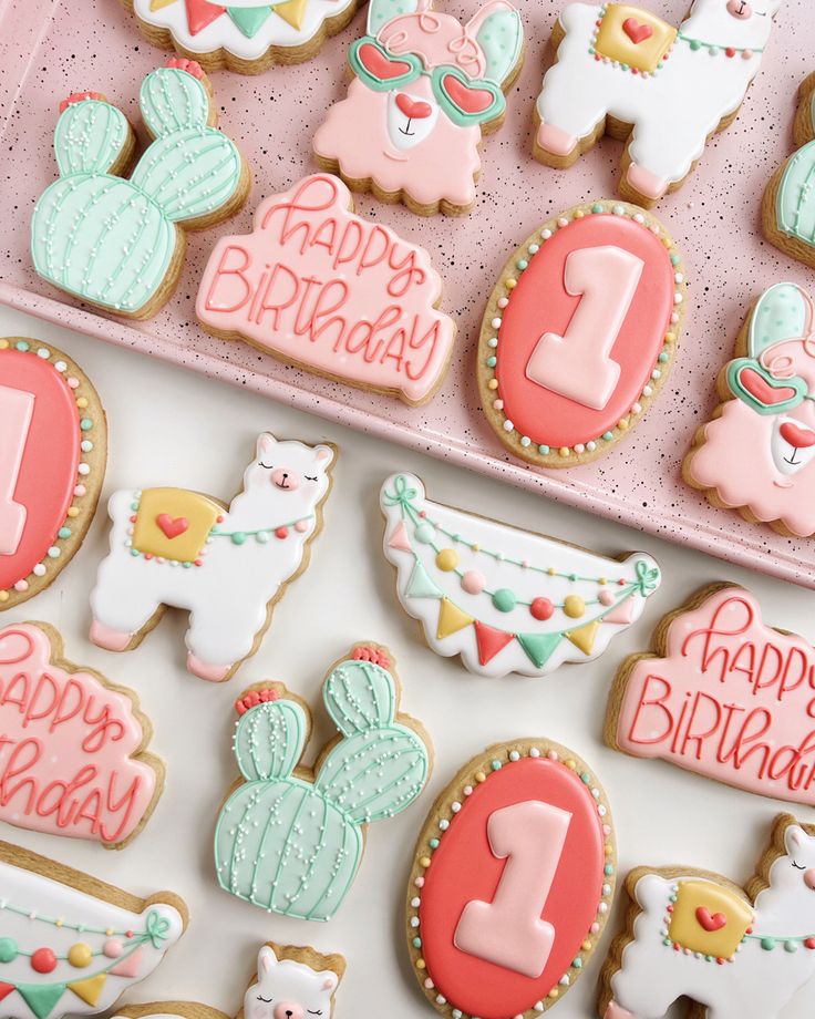 decorated birthday cookies in a pink box with the number one on it and other decorations