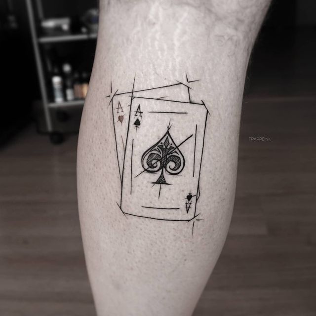 a black and white photo of a playing card tattoo on the leg