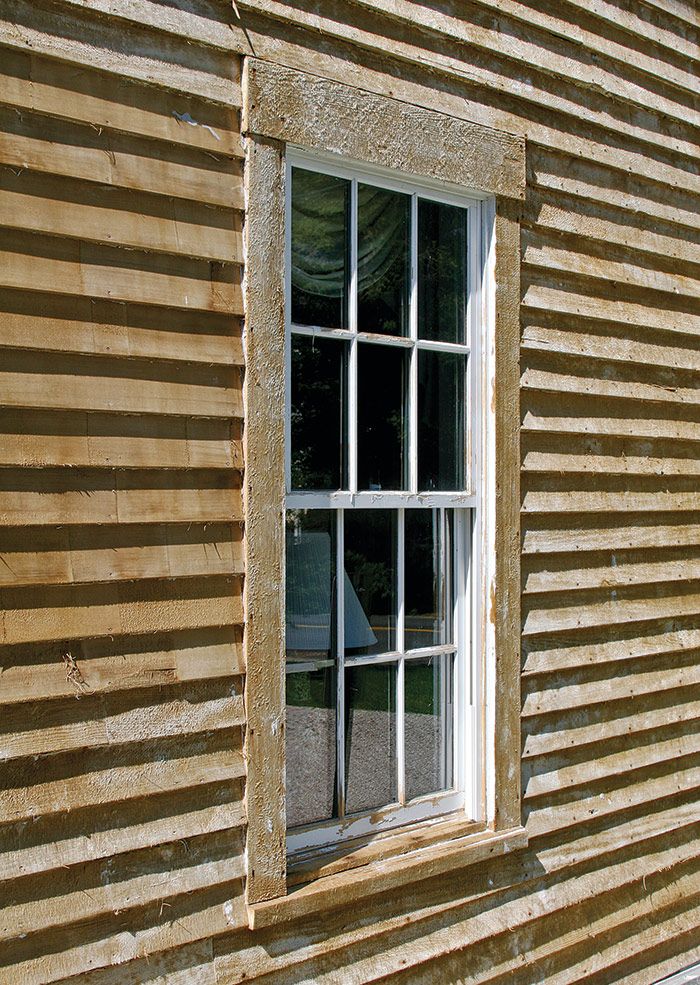 an old wooden building with a window that is partially closed and missing the panes