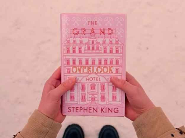 a person holding up a pink book in front of their face with the words, the grand overlook hotel written on it