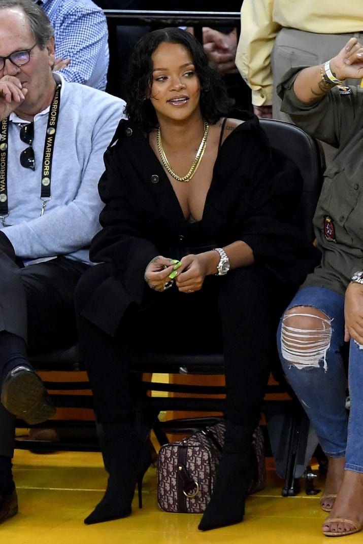 an image of a woman sitting on a bench in front of other people at a basketball game