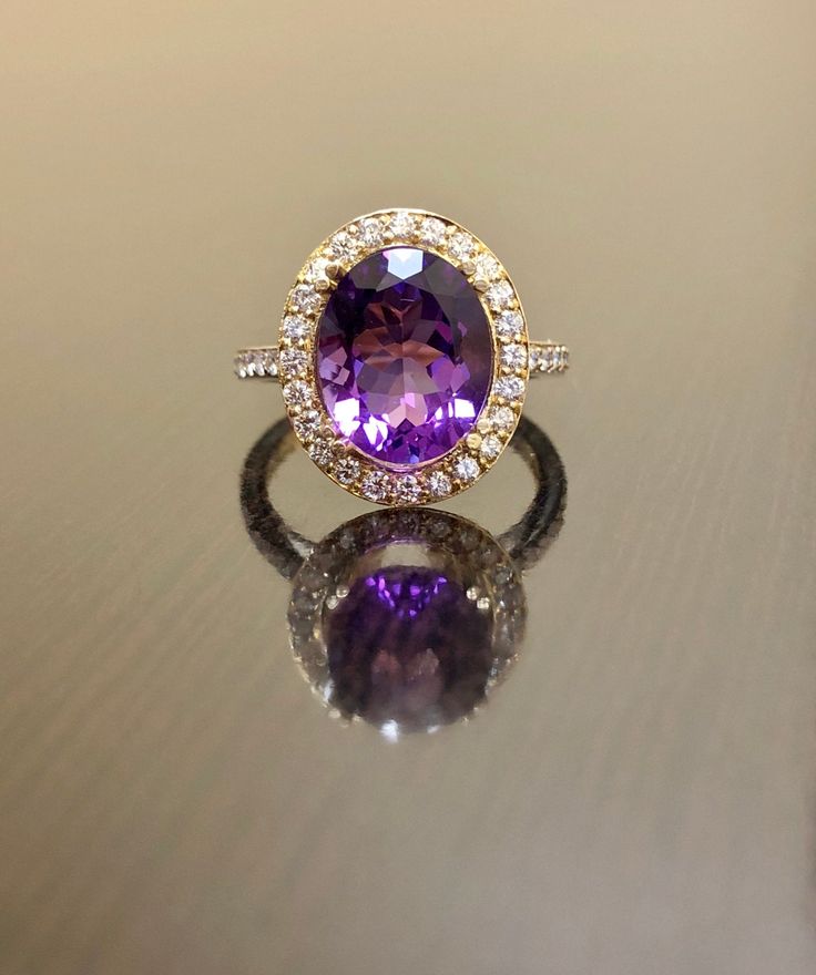 an oval shaped amethorate and diamond ring sitting on top of a table