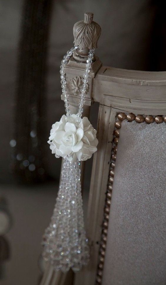 a white flower hanging from the side of a chair with beaded trimmings