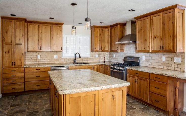 a large kitchen with wooden cabinets and marble counter tops, along with an island in the middle