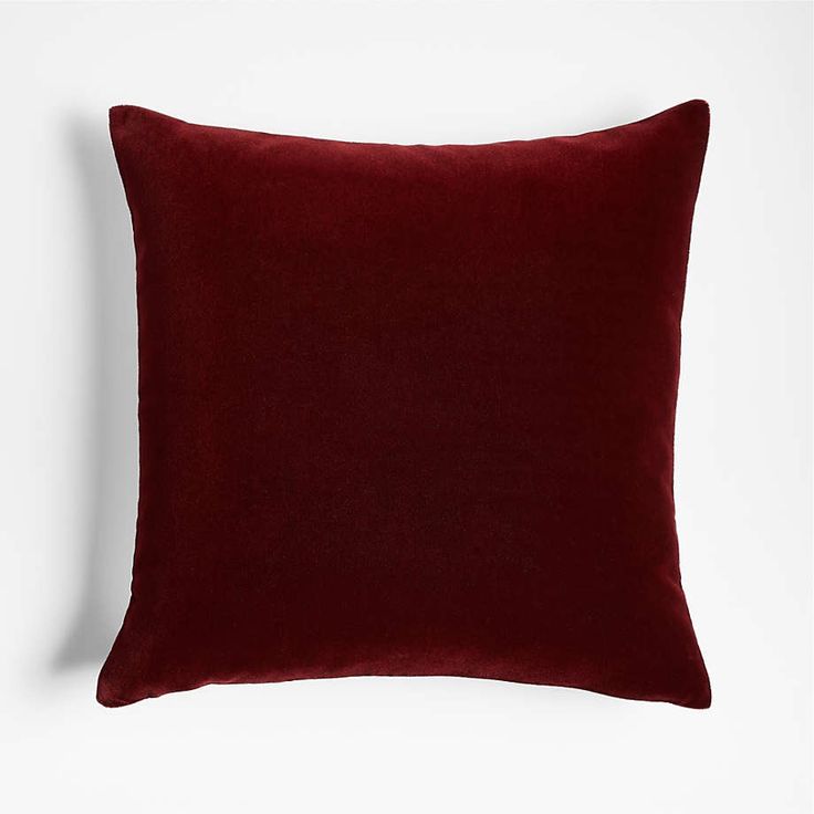 a dark red pillow on a white wall with no one in the room to see it