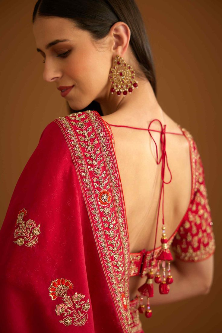 Editor's Note The combination of a red brocade blouse with zardozi embroidery and a silk chanderi sari with zardozi embroidery creates a stunning traditional look. The blouse adds a pop of bold color with intricate detailing, while the sari adds elegance with delicate embroidery. Color: Red Fabric: Silk and chanderi Embroidery details: Zardozi embroidery Components: Sari & blouse Sari length: 6 meters, sari width: 46" inches Occasion: Engagement and wedding guest Disclaimer: Product color may sl Red Brocade Blouse, Red Sari, Blouse Sari, Blouse Yoke, Zardozi Embroidery, Brocade Blouse, Personal Shopping Service, Brocade Blouses, Delicate Embroidery