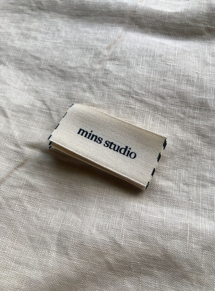 a piece of cloth with the words minis studio on it sitting on a bed