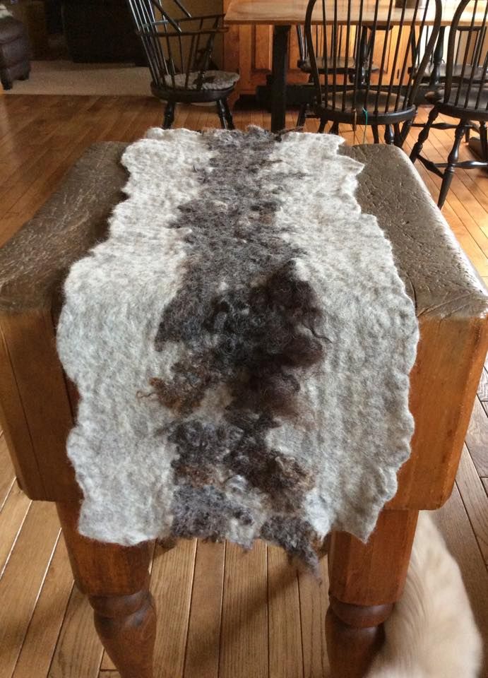 a cat sitting on top of a wooden floor next to a table covered in fur