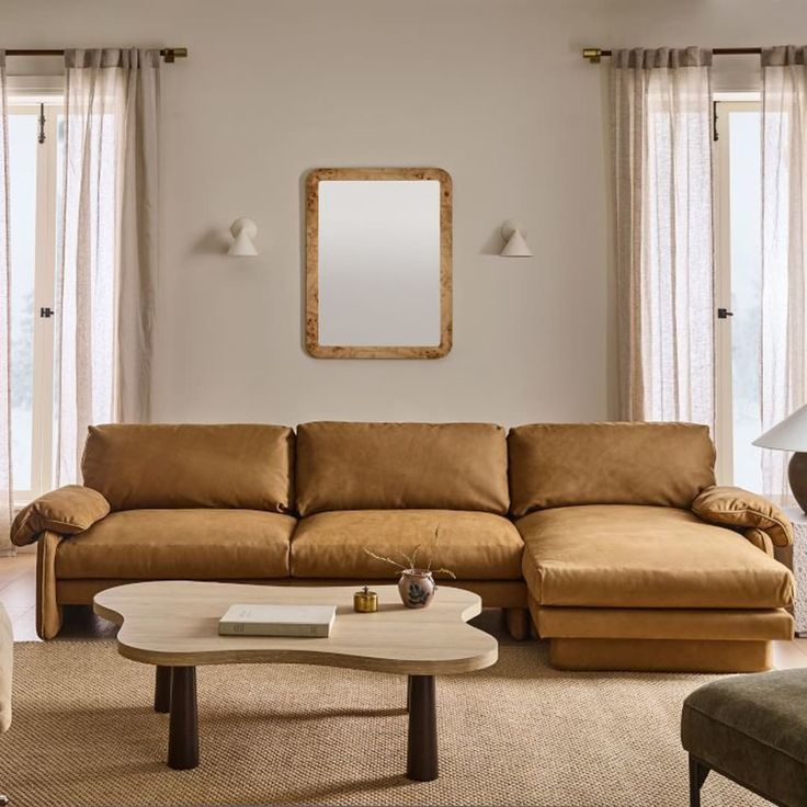 a living room filled with furniture and a large mirror on the wall above the couch