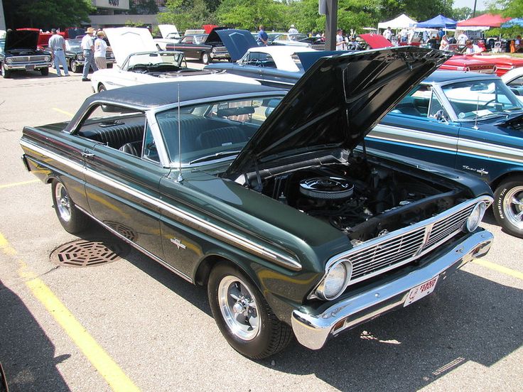 an old car with its hood open parked in a parking lot next to other cars