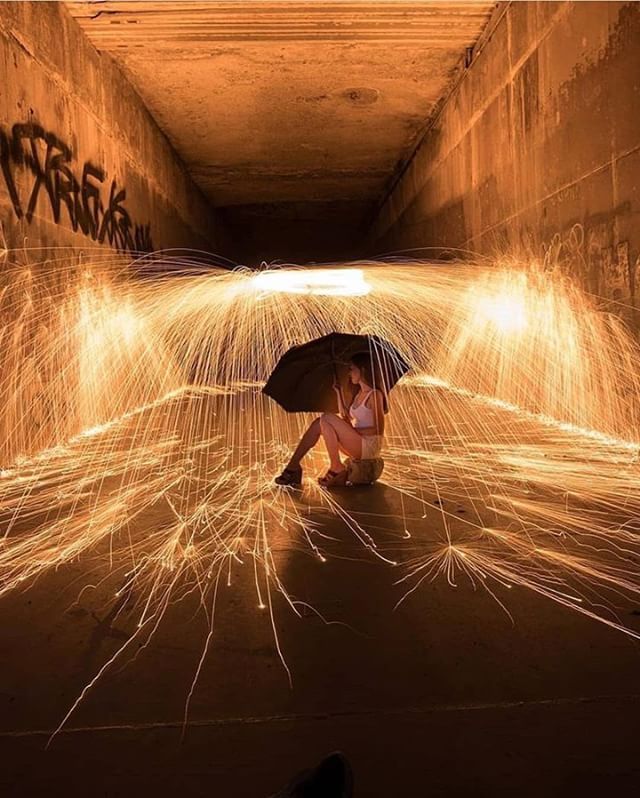 a woman sitting on the ground with an umbrella in front of her and light painting