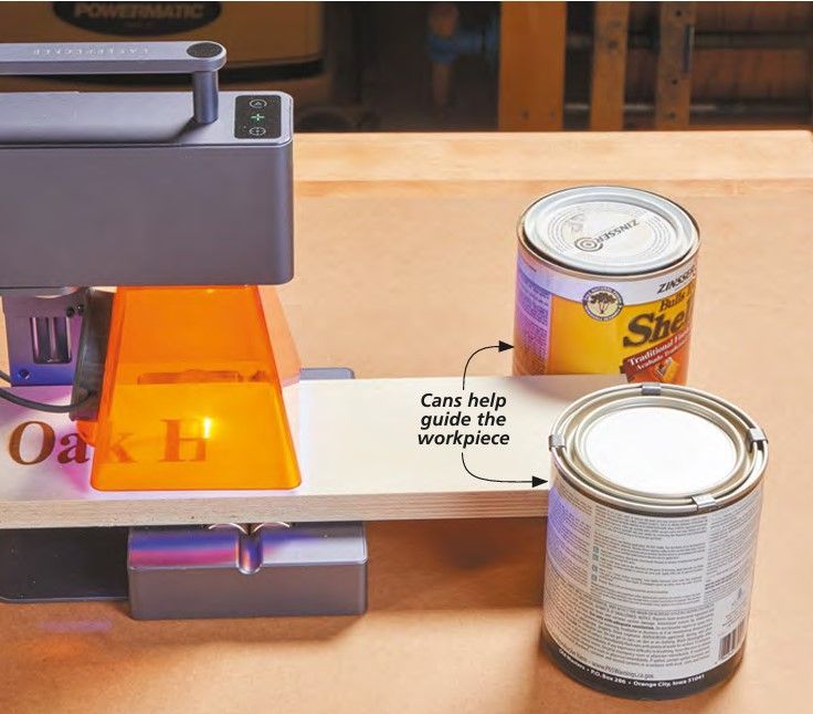 a can of paint next to a printer and some other items on a table top