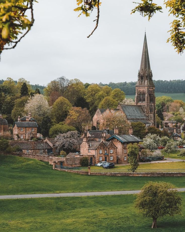 an old church in the middle of a small town with lots of green grass and trees