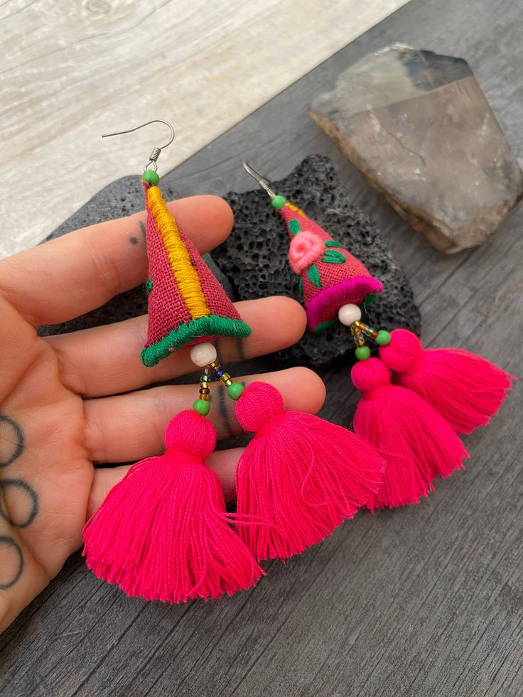 Long fun pink tassel earrings. Made with fabric, string, stitching technique and pink tassels. Creating this one of a kind long pair of earrings with a 3D triangular shape in the middle with a flower design on it and 2 fun pink tassels. This pair will rock your outfit. They are big and a powerful statement pair of earrings, but at the same time they are super light what makes them easy to wear. The earrings are 10cm- 4 inch long in total. The main triangular part is 4.3cm-1.75 inch long 2.5cm- 1 Hot Pink Earrings, Pink Tassel Earrings, Embroidered Earrings, Wiccan Necklace, Mens Gemstone Rings, Earrings Big, Long Tassel Earrings, Pink Tassel, Skull Necklace