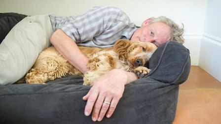 a man laying on top of a dog bed with two dogs next to his face