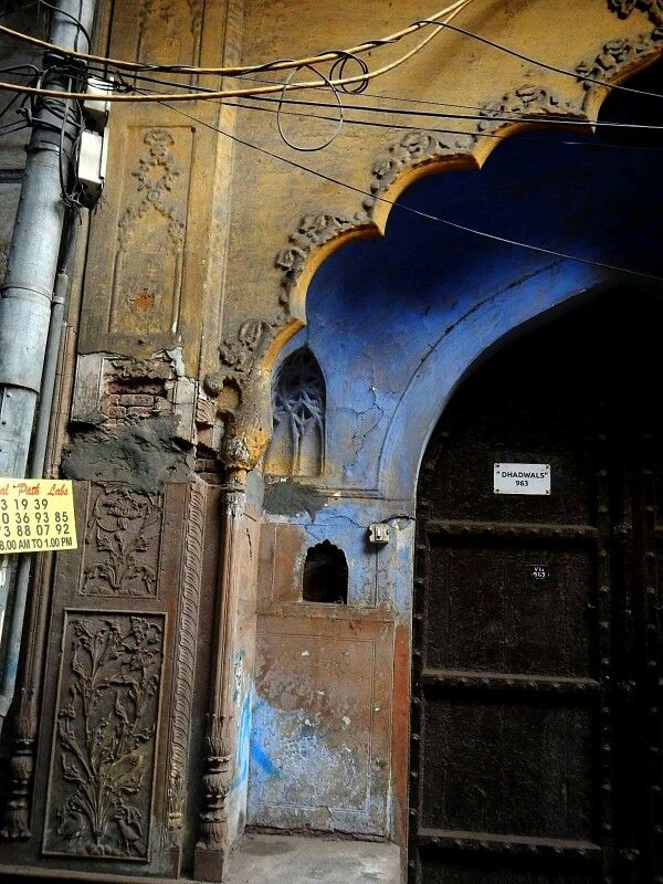 the entrance to an old building with blue and yellow paint on it's walls