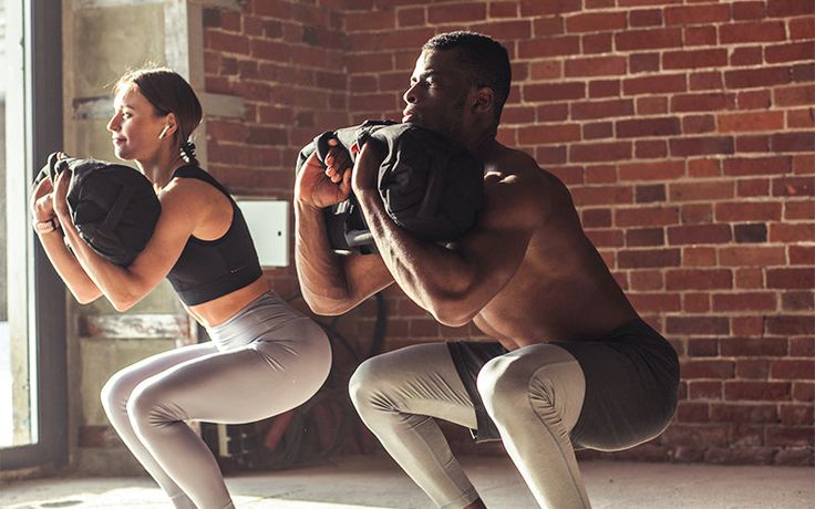 a man and woman doing squats in front of a brick wall