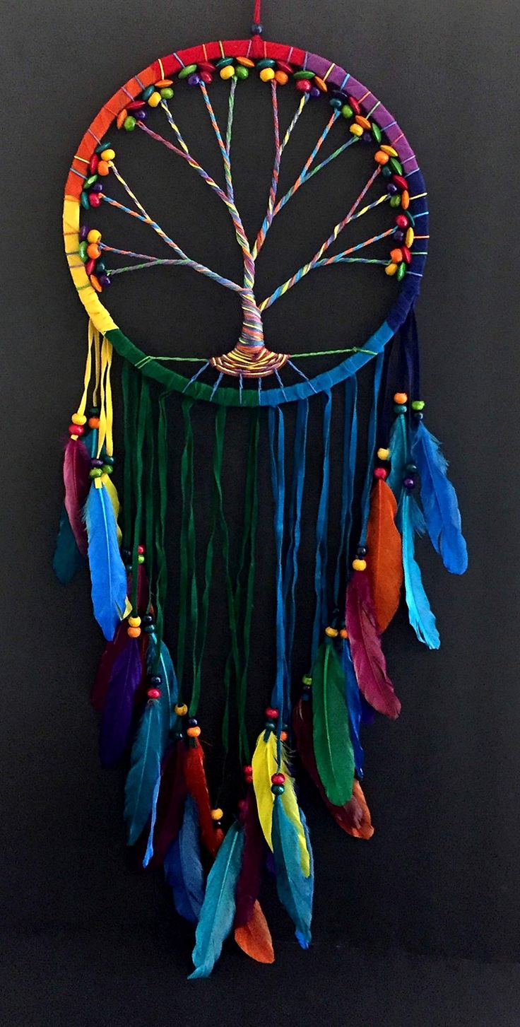 a colorful dream catcher with feathers hanging from it's side on a black background