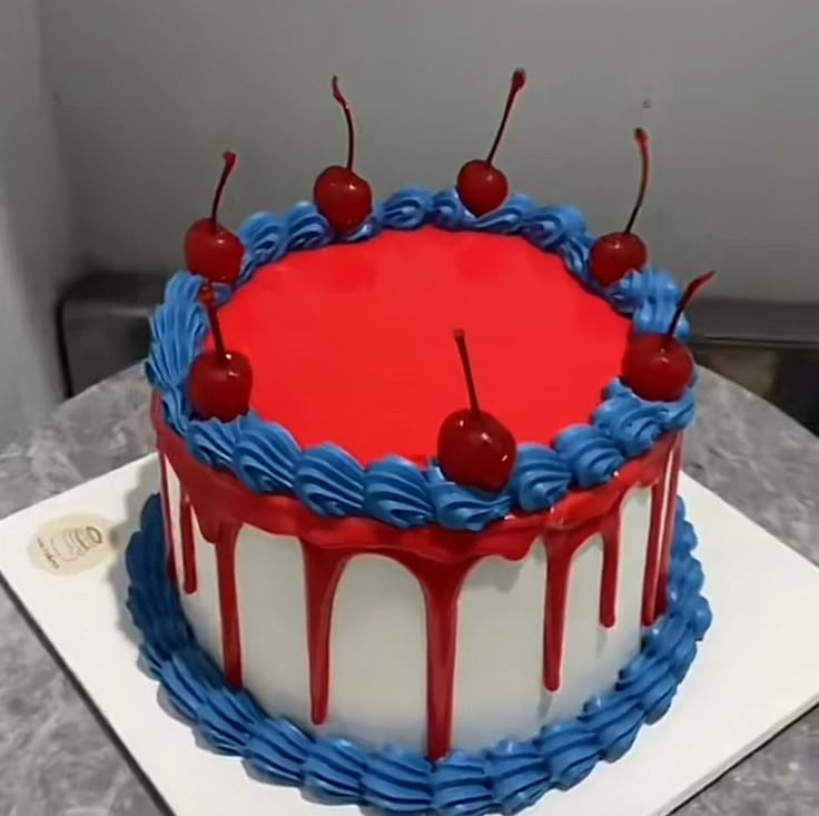 a red, white and blue cake with cherries on top is sitting on a table