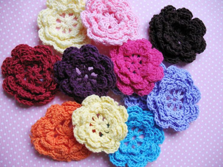 several crocheted flowers are arranged on a table