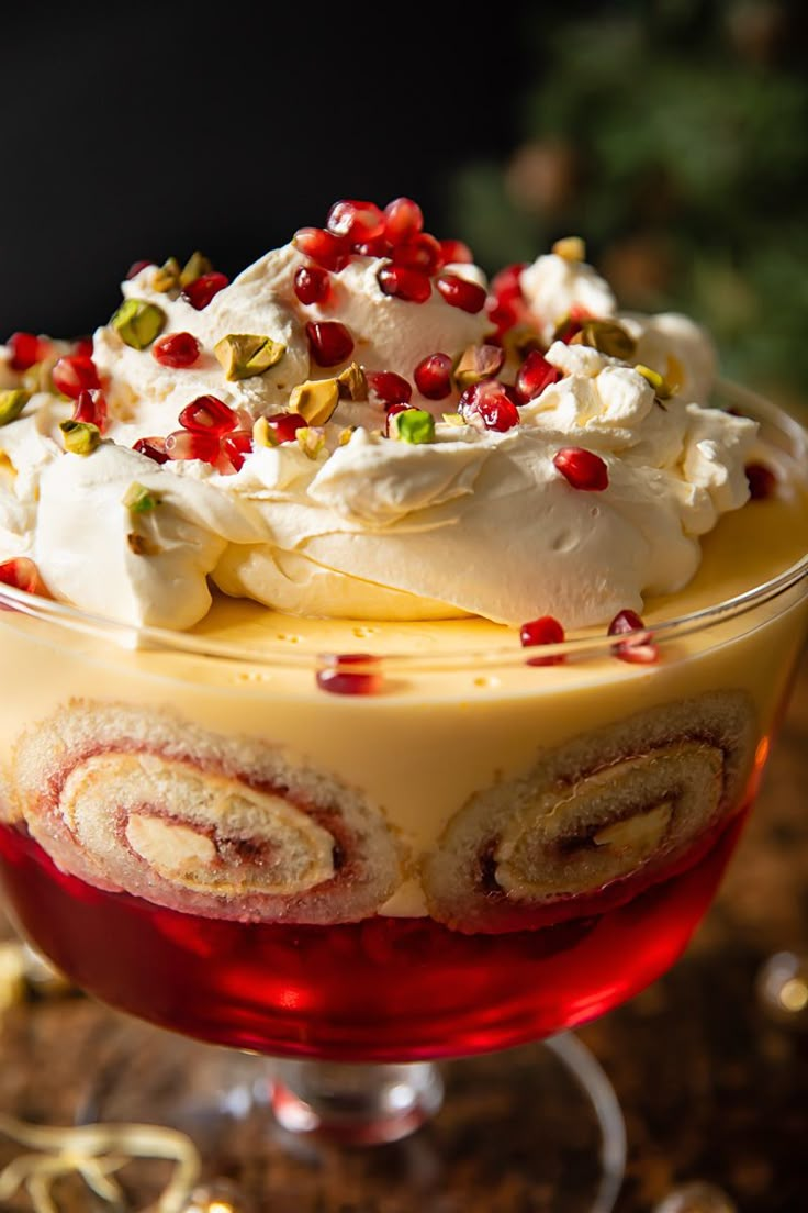 a dessert dish with whipped cream and pomegranates on the top, surrounded by christmas decorations