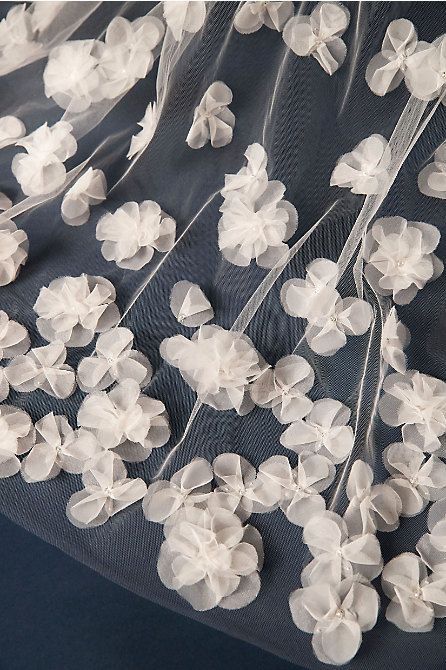 white flowers are attached to the sheer fabric