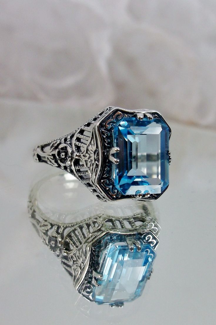 Natural Blue Topaz Ring  Lovely Rectangle Design#148 Size 4 In Stock This is a brand new Edwardian reproduction filigree ring in sterling silver. The emerald cut high quality natural genuine sky blue topaz gemstone is 9mm by 7mm, (approximately 2.88ct). The inside of the band is marked 925 for sterling silver. Notice the beautiful intricate floral daisy design of the filigree etched band. A gift box is included and all rings are shipped in the box for safekeeping. This ring can be sized by any j Classic Blue Topaz Ring With Rectangular Stone, Silver Topaz Ring With Rectangular Blue Stone, Silver Blue Topaz Ring With Rectangular Stone, Sterling Silver Topaz Ring With Rectangular Stone For Formal, Formal Sterling Silver Topaz Ring With Rectangular Stone, Gift Blue Topaz Ring With Rectangular Shape, Gift Blue Topaz Rectangular Ring, Rectangular Blue Topaz Gemstone Ring, Classic Blue Rectangular Topaz Ring