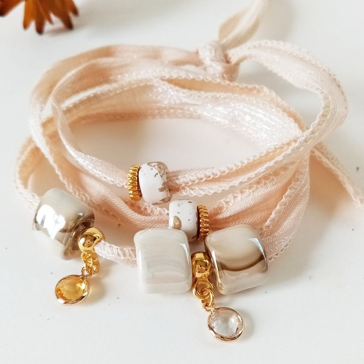 Casual Bracelet in beige and ecru tones, bohemian and romantic style. This boho bracelet is inspired by the streets of Paris. It is a very modern and youthful bracelet but it has an elegant and cool touch. It is made with a 65 cm long cotton ribbon where several Greek porcelain beads in beige-gold tones have been inserted and combined with several different types of golden charms. This wraparound bracelet wraps around your wrist three times and ties at the back. It can also be used as a necklace Bohemian Wrap Bracelet With Adjustable Length As Gift, Adjustable Bohemian Wrap Bracelet As Gift, Bohemian Beige Bracelet For Festivals, Elegant Adjustable Festival Bracelets, Elegant Adjustable Bracelets For Festivals, Elegant Handmade Friendship Bracelets For Festivals, Bohemian Bracelets With Adjustable Length As Gift, Bohemian Adjustable Bracelets For Gifts, Bohemian Bracelets With Adjustable Length