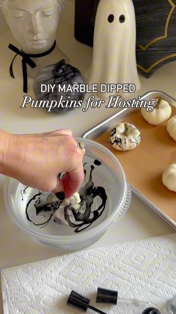 someone is dipping marshmallows into a bowl on a table with halloween decorations