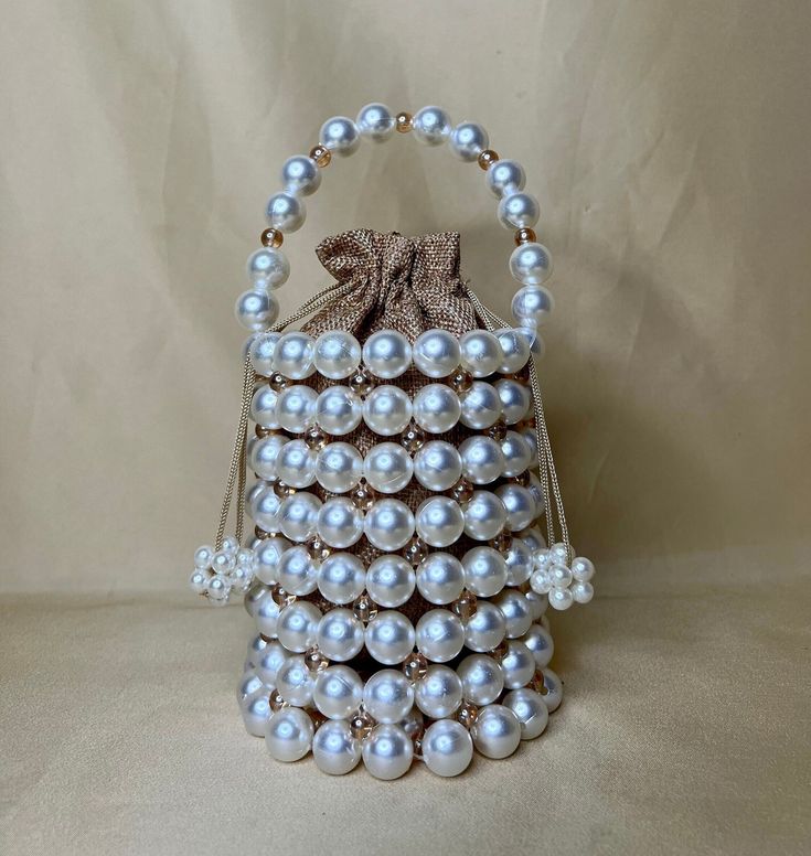 Every lady needs a pearl bucket bag. DETAILS 100% Pearls and gold beaded bag. -Completely handmade in Canada -High quality, non-fading statement beads. -Comes with a linen pouch inside. -Fits phone, cards and essential make-up. -All orders are packaged beautifully. SIZE 30.5cm x 22.9cm x 10.2cm IDEAL FOR -Ideal as a gift for friend, family and lover. -Also ideal for weddings and parties. SHIPPING -We are trying our best to process all orders received on the SAME BUSINESS DAY. -If you have your p White Bucket Bag For Evening, Evening Rectangular Bucket Bag With Pearl Handle, White Formal Pouch Bucket Bag, Formal White Pouch Bucket Bag, White Pouch Bucket Bag For Evening, White Evening Pouch Bucket Bag, White Evening Bucket Bag Pouch, Elegant Bucket Bag For Party, White Handheld Bucket Bag For Gift