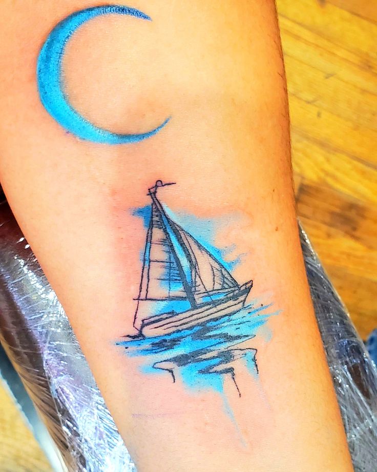 a small sailboat with a crescent moon tattoo on the arm