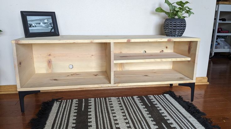 a wooden entertainment center sitting on top of a hard wood floor next to a potted plant