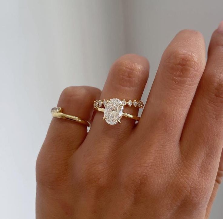 a woman's hand holding a ring with a diamond in the middle and two diamonds on it