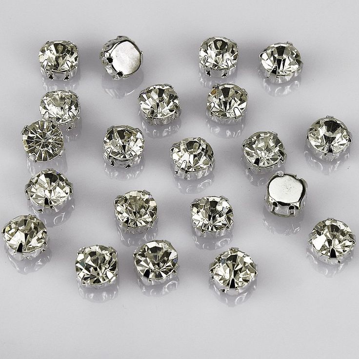 many different sizes and shapes of diamonds on a white surface with reflection in the middle