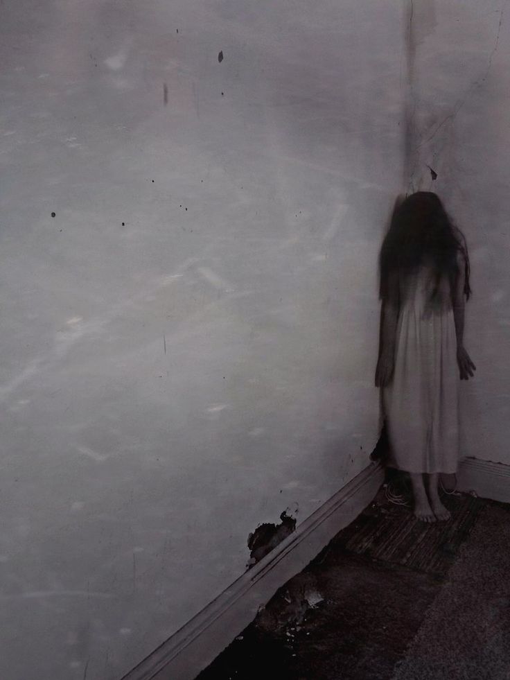 a woman standing in front of a wall with her hands on the floor and head down