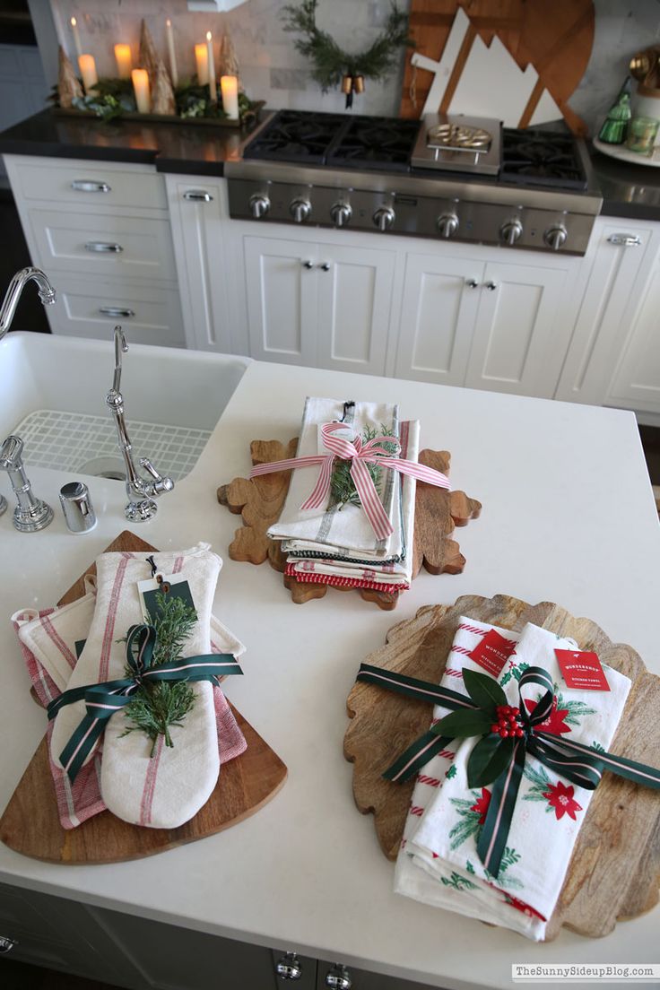 christmas napkins are wrapped in green and red bows on wood slices, sitting on a kitchen counter